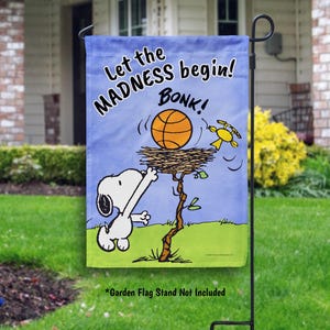 Peut inclure: Un drapeau de jardin bleu avec Snoopy de Peanuts, tendant la main vers un ballon de basket dans un nid. Le drapeau indique "Let the MADNESS begin! BONK !" avec un oiseau jaune volant à proximité. Le drapeau est sur un support en métal noir.