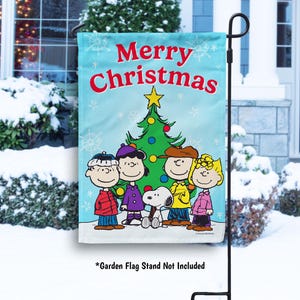 May include: A blue and white garden flag with a Christmas tree and the Peanuts characters. The flag reads "Merry Christmas".