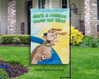 May include: A garden flag with a cartoon dog driving a car. The dog is brown with a pink tongue sticking out. The flag has the text "Life's a journey enjoy the ride!" on it.