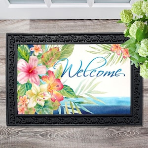 May include: A welcome mat with a tropical floral design and the word "Welcome" in blue script. The mat has a black border with a decorative pattern.