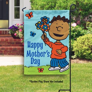 Pode incluir: Uma bandeira de jardim azul e verde com um personagem de desenho animado segurando flores. A bandeira diz "Feliz Dia das M&atilde;es".