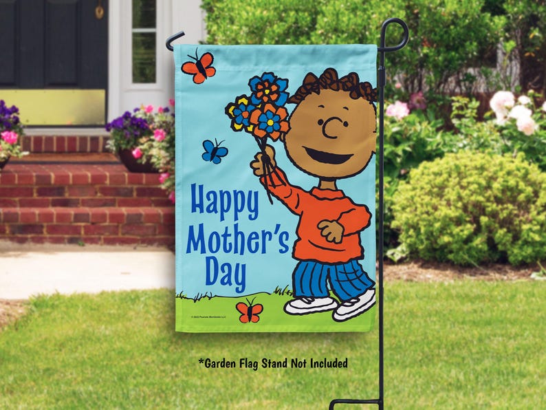 Pode incluir: Uma bandeira de jardim azul e verde com um personagem de desenho animado segurando flores. A bandeira diz "Feliz Dia das M&atilde;es".
