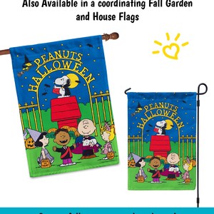 Op de afbeelding: Een Peanuts Halloween-tuin vlag met een blauwe achtergrond en een groen gazon. De vlag toont Snoopy verkleed als een vampier, Charlie Brown, Lucy, Linus en Sally verkleed in Halloween-kostuums. De tekst "PEANUTS HALLOWEEN" staat in een cirkel bovenaan de vlag.