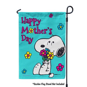 May include: A turquoise blue garden flag with the text "Happy Mother's Day" in pink and black lettering. A cartoon image of Snoopy holding a bouquet of flowers is in the bottom right corner of the flag.