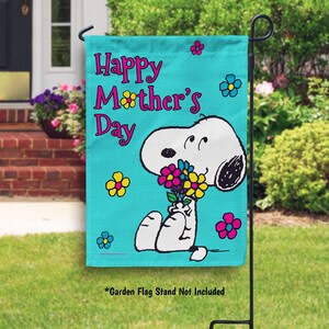 May include: A blue garden flag with a white outline of Snoopy holding a bouquet of pink, yellow, and purple flowers. The text "Happy Mother's Day" is written in pink and black letters.