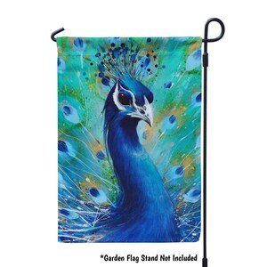 K&ouml;nnte beinhalten: Eine Gartenflagge mit einem blauen Pfau auf einem leuchtend blauen und gr&uuml;nen Hintergrund. Der Kopf des Pfaus ist zur Seite gedreht, und seine Federn sind hinter ihm ausgebreitet. Die Flagge ist mit einem Aquarell-Effekt bedruckt.