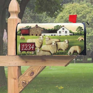 May include: A mailbox with a farmhouse and sheep design. The mailbox is made of metal and has a black flag with a red star. The mailbox has a red and white number plate with the number 1234 on it.