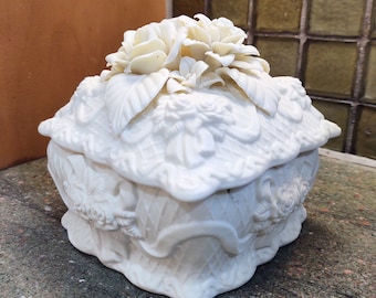 Puede incluir: Caja de porcelana blanca con un diseño floral. La caja está decorada con tres rosas blancas y detalles intrincados.