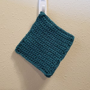 May include: A teal crocheted dishcloth hanging on a white hook.