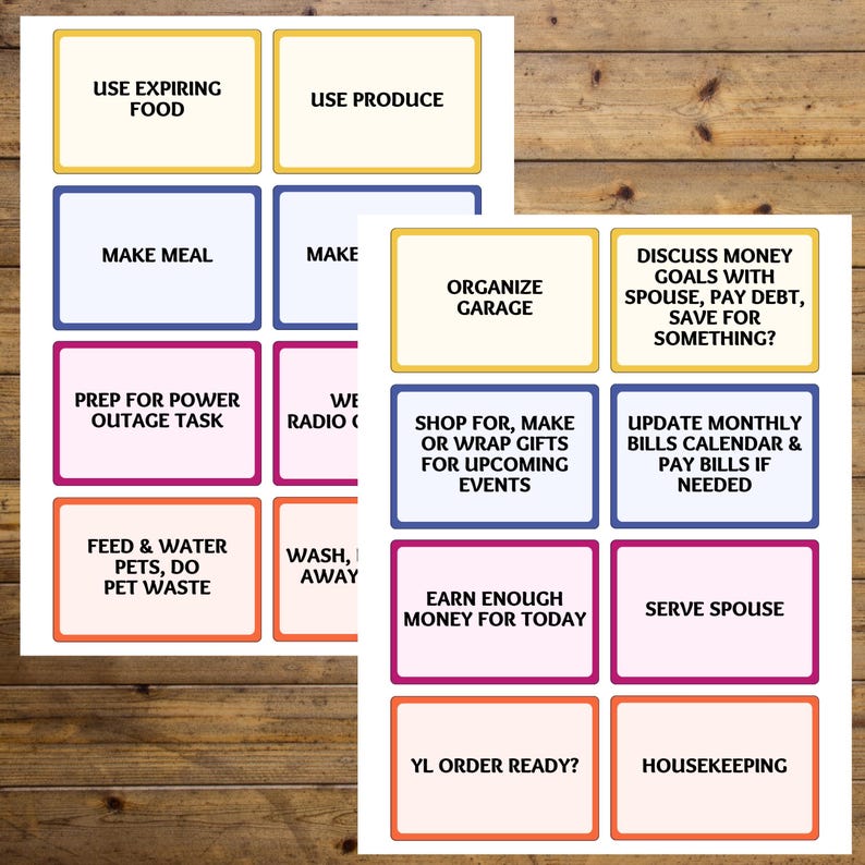 May include: Two sheets of paper with colorful rectangular boxes containing text. The text includes phrases like "Use Expiring Food," "Make Meal," "Organize Garage," and "Prep for Power Outage Task." The background is a wooden surface.