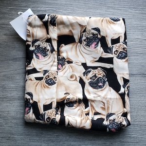 May include: Black fabric with a repeating pattern of pugs. The pugs are in various poses and are all facing forward. The fabric is soft and has a smooth texture.