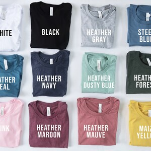 Puede incluir: Una colecci&oacute;n de camisetas plegadas en varios colores: blanco, negro, gris jaspeado, azul acero, azul verdoso jaspeado, azul marino jaspeado, azul polvoriento jaspeado, bosque jaspeado, rosa, granate jaspeado, malva jaspeado y amarillo ma&iacute;z. Cada camiseta tiene una etiqueta con su color.