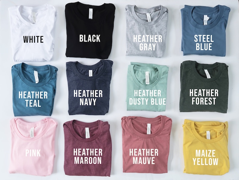 Puede incluir: Una colecci&oacute;n de camisetas plegadas en varios colores: blanco, negro, gris jaspeado, azul acero, azul verdoso jaspeado, azul marino jaspeado, azul polvoriento jaspeado, bosque jaspeado, rosa, granate jaspeado, malva jaspeado y amarillo ma&iacute;z. Cada camiseta tiene una etiqueta con su color.