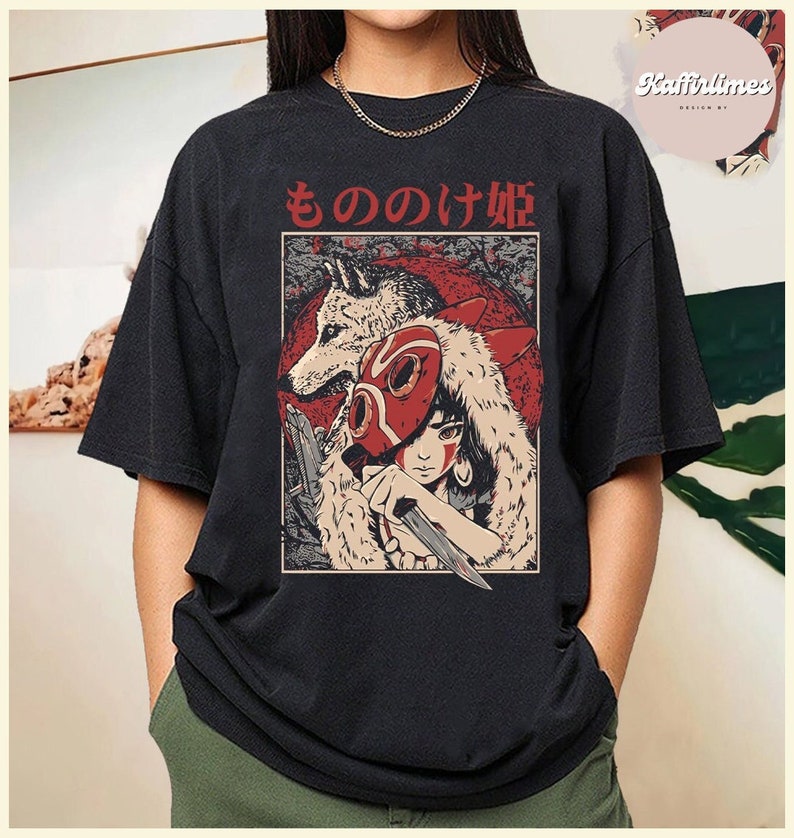 Op de afbeelding: Zwart t-shirt met een Japanse anime-stijl illustratie. Het ontwerp bevat een wolf, een personage met een rood masker en Japanse tekst. De illustratie staat tegen een rode achtergrond.