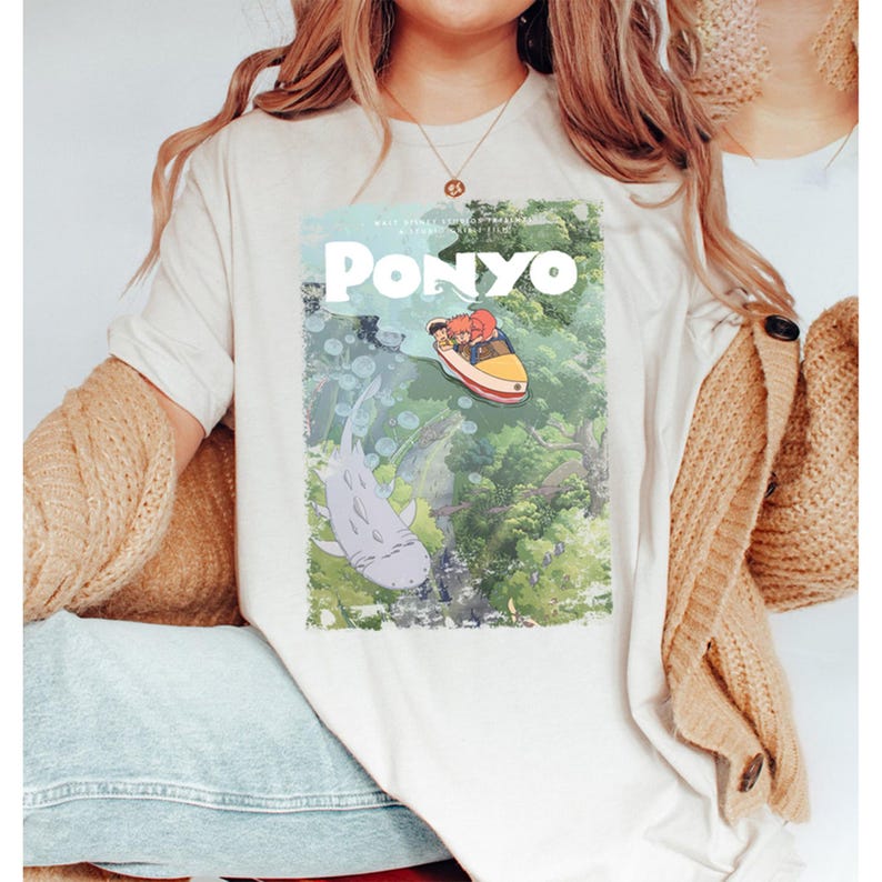 Puede incluir: Camiseta color crema con un dise&ntilde;o gr&aacute;fico de la pel&iacute;cula de animaci&oacute;n "Ponyo". El dise&ntilde;o incluye el t&iacute;tulo "Ponyo" en blanco, un barco con dos personajes, un gran pez gris y una exuberante escena submarina.
