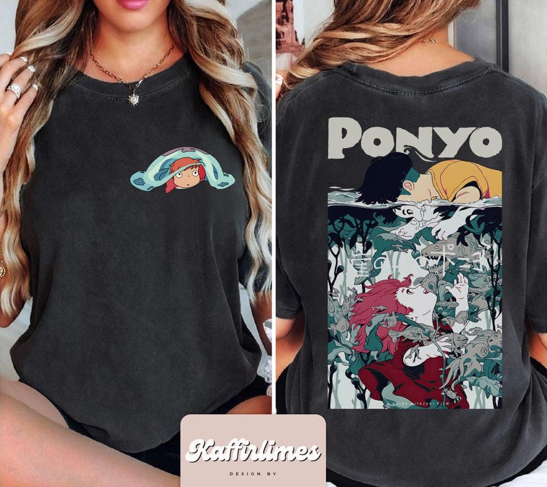 May include: Dark grey t-shirt with a small cartoon graphic on the front and a larger illustration on the back. The front graphic shows a character under a blue blanket. The back features the word "PONYO" and a colourful anime-style illustration.