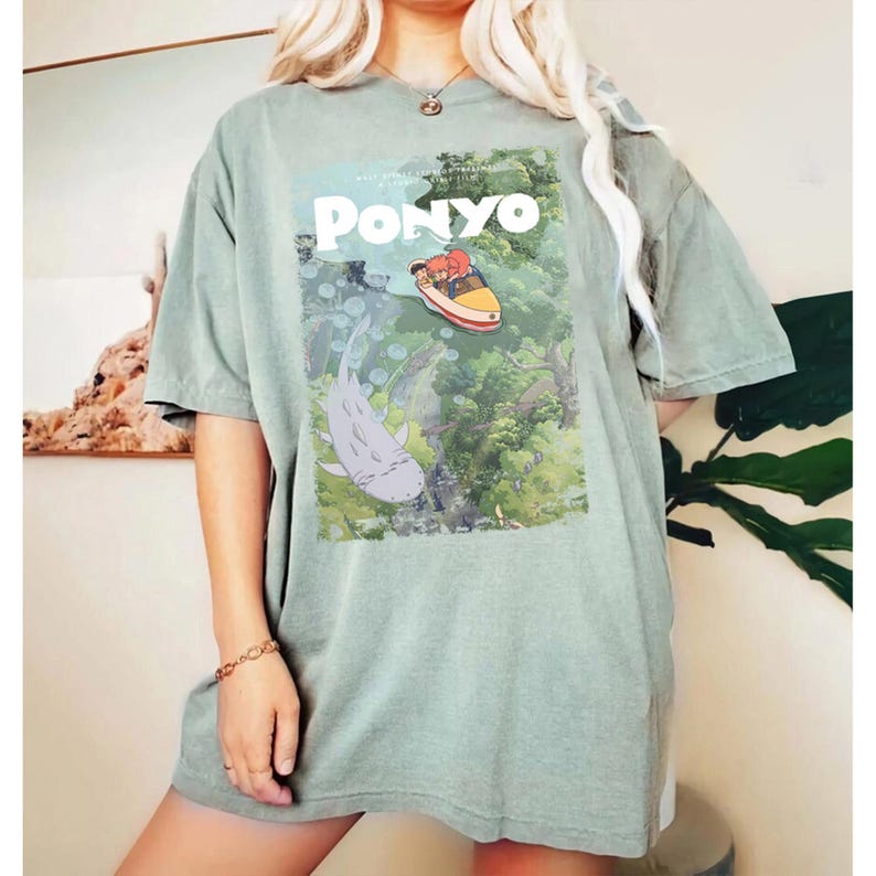 Puede incluir: Camiseta verde salvia con un gr&aacute;fico de la pel&iacute;cula de animaci&oacute;n "Ponyo". El dise&ntilde;o incluye el t&iacute;tulo de la pel&iacute;cula, una representaci&oacute;n de Ponyo y otros personajes en una escena submarina. La camiseta es de corte holgado.