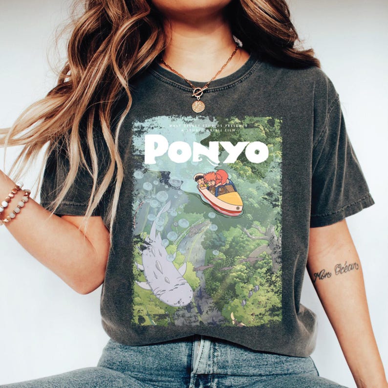 Puede incluir: Camiseta gris oscuro con un gr&aacute;fico de la pel&iacute;cula de animaci&oacute;n "Ponyo". El dise&ntilde;o incluye el t&iacute;tulo de la pel&iacute;cula, un barco con personajes y vida marina. La camiseta tiene un aspecto vintage y desgastado.