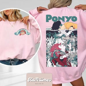 May include: Pale pink sweatshirt with a graphic from the animated film "Ponyo." The front has a small cartoon graphic, while the back displays a larger, colourful illustration with the film's title. The sweatshirt is a soft, casual style.