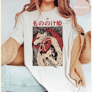 Op de afbeelding: Cr&egrave;mekleurig T-shirt met een Japanse illustratie in anime-stijl. De afbeelding bevat een wolf, een personage met een rood masker en Japanse tekst. Het ontwerp is geplaatst tegen een rode achtergrond met een bosachtig patroon.