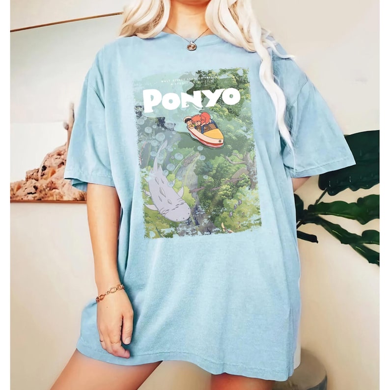 Puede incluir: Camiseta azul claro con un gr&aacute;fico de la pel&iacute;cula de animaci&oacute;n "Ponyo". El dise&ntilde;o incluye el t&iacute;tulo de la pel&iacute;cula e im&aacute;genes de personajes y escenas de la pel&iacute;cula. La camiseta es de corte holgado, con mangas cortas.