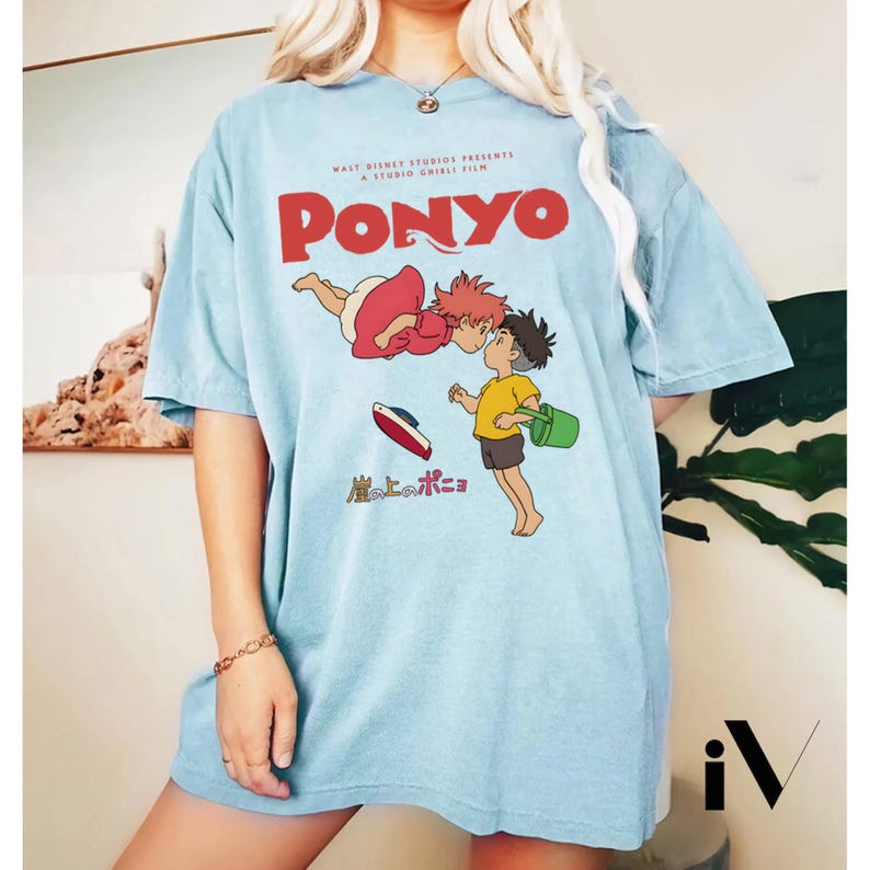 May include: Light blue t-shirt featuring the animated film "Ponyo." The shirt displays the film's title in red, along with an illustration of the characters. The shirt is a short-sleeved, casual style.