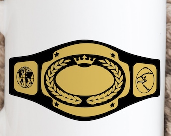 May include: White ceramic mug featuring a championship belt design. The belt is black and gold, with a central oval, laurel wreath, stars, a globe, and an eagle head. The mug has a curved handle.