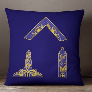 Può includere: Un cuscino blu con tre disegni decorativi dorati. I disegni sono un triangolo, un quadrato e un rettangolo. I disegni sono tutti intricati e hanno un motivo floreale.