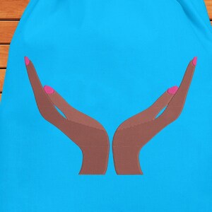 May include: A blue drawstring bag with a graphic of two brown hands with pink fingernails, cupped together.