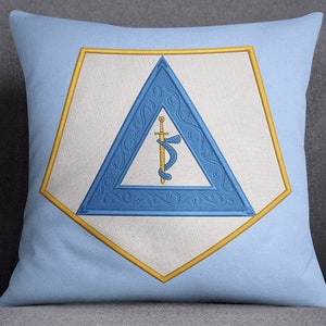 Puede incluir: Una almohada azul y dorada con un símbolo masónico bordado. El símbolo es un triángulo que contiene una espada y una serpiente.