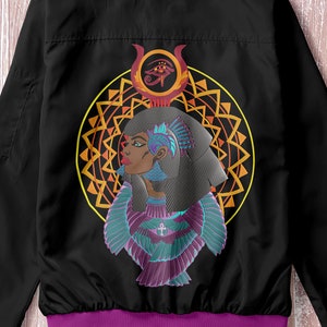 May include: Black bomber jacket with a purple collar and cuffs. The back of the jacket features a colorful design of a woman with wings, an eye, and a geometric pattern.