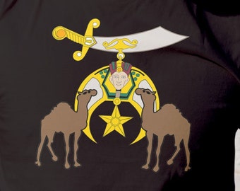 Könnte beinhalten: Ein schwarzes T-Shirt mit einem goldenen und weißen Design, das einen Halbmond, einen fünfzackigen Stern und zwei Kamele zeigt. Das Design ist ein Symbol der Shriners.