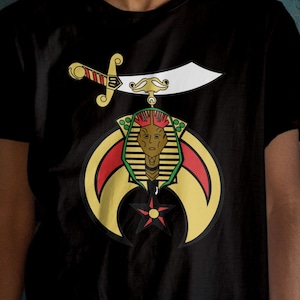 May include: A black t-shirt with a gold, red, and green graphic of a crescent moon, a five-pointed star, and a pharaoh's head with a scimitar above it.