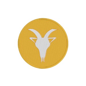 Op de afbeelding: Een gele ronde patch met een wit geborduurd beeld van een geitenkop.