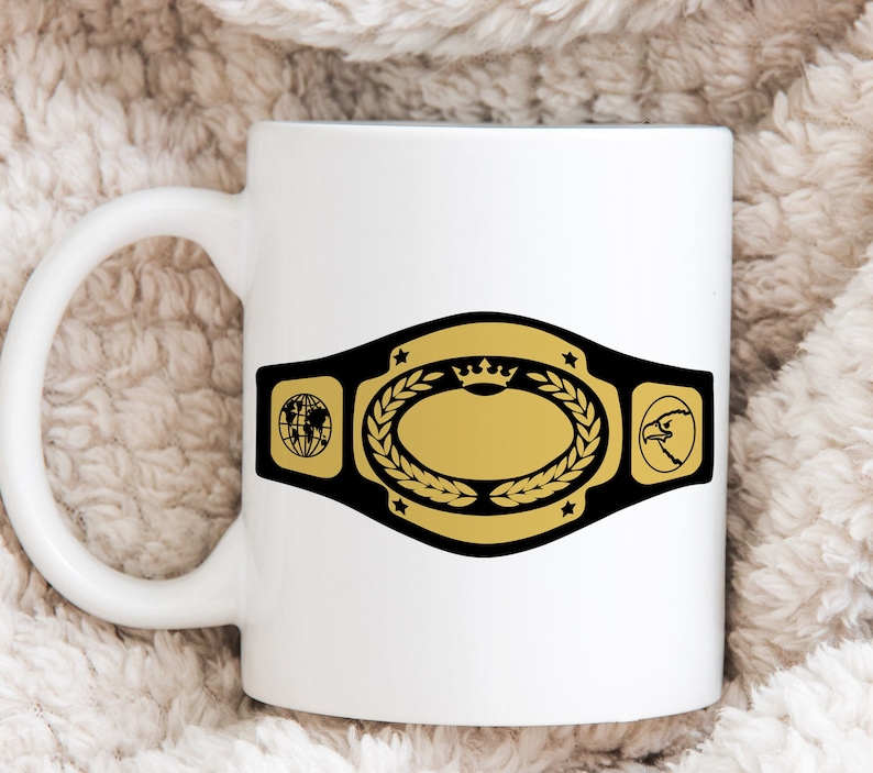 May include: White ceramic mug featuring a championship belt design. The belt is black and gold, with a central oval, laurel wreath, stars, a globe, and an eagle head. The mug has a curved handle.