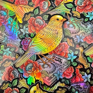 May include: A holographic sticker featuring a yellow bird perched on a music mixer with the text "Pretty Lights" and surrounded by colorful flowers.
