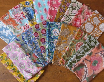 May include: A collection of 15 colorful fabric napkins with floral and paisley patterns. The napkins are arranged in a fan shape and feature a variety of colors, including blue, green, pink, yellow, and orange.