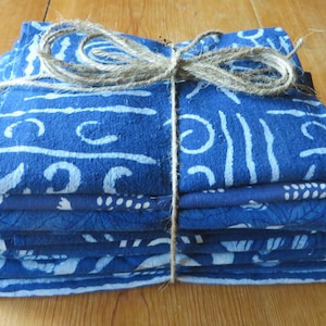 May include: A stack of blue and white fabric squares with a white pattern, tied together with twine.