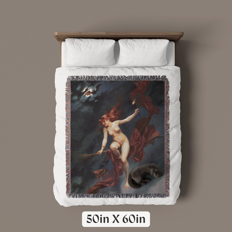 May include: A woven tapestry throw blanket featuring a vintage illustration of a woman flying on a broomstick with a black cat. The woman is wearing a red robe and has long red hair. The background is a dark blue night sky with stars and a crescent moon.