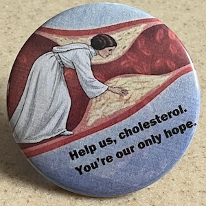 Op de afbeelding: Ronde knoop met een vintage illustratie van een persoon in een wit gewaad die uitreikt naar een afbeelding van een verstopte slagader. Tekst luidt: "Help us, cholesterol. You're our only hope."