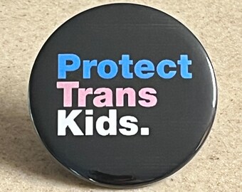 May include: A black button with the text "Protect Trans Kids." in blue, pink, and white lettering.
