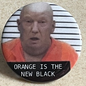 May include: A round button with a photo of a man in an orange jumpsuit with the text "ORANGE IS THE NEW BLACK" printed on the bottom.