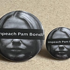 May include: Two round black and white buttons. The buttons feature a grayscale image of a person with a black bar across the eyes. The text "Impeach Pam Bondi" is printed in white on the black bar.