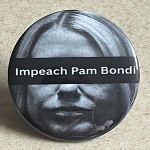 May include: A round, black and white button with the text "Impeach Pam Bondi" in white letters on a black banner. The button features a grayscale image of a person's face.