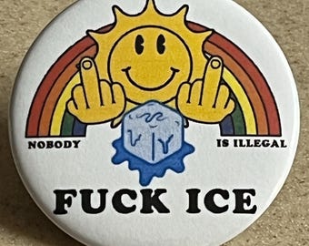 Puede incluir: Un botón blanco con un sol de dibujos animados, un arcoíris y un cubo de hielo. El texto dice "NOBODY IS ILLEGAL" y "FUCK ICE". El sol es amarillo y muestra el dedo medio.