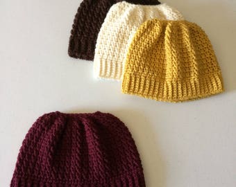 Peut inclure: Quatre bonnets en crochet de différentes couleurs : marron, blanc, jaune et bordeaux. Les bonnets sont tous du même style, avec un design côtelé simple.