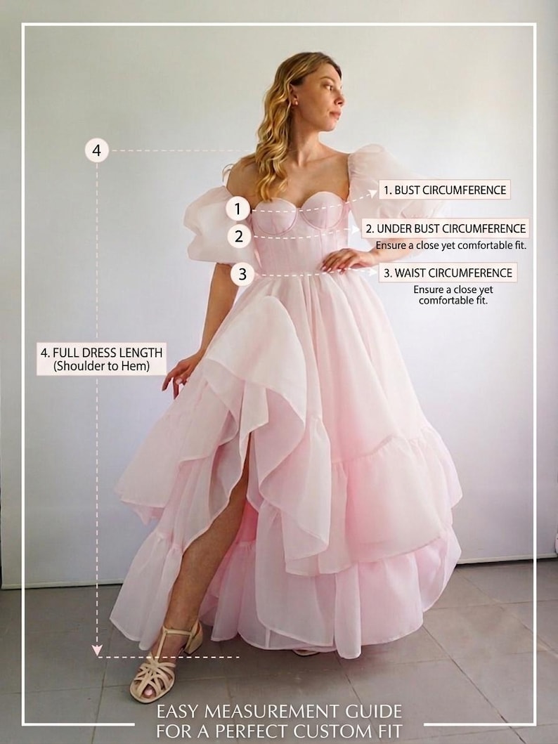 May include: A light pink, floor-length dress with puff sleeves, a sweetheart neckline, and a layered, ruffled skirt with a high side slit. The image includes a measurement guide labeled 1. BUST CIRCUMFERENCE, 2. UNDER BUST CIRCUMFERENCE, 3. WAIST CIRCUMFERENCE, and 4. FULL DRESS LENGTH (Shoulder to Hem), with the text EASY MEASUREMENT GUIDE FOR A PERFECT CUSTOM FIT.
