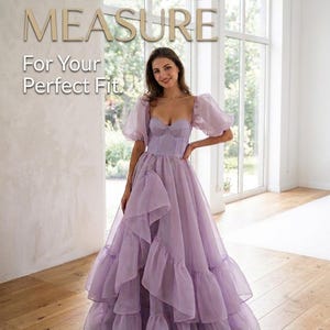 May include: A floor-length lavender gown featuring a structured corset-style bodice, sheer puff sleeves, and a voluminous skirt with layered ruffles. The text "MADE TO MEASURE For Your Perfect Fit" is visible at the top of the image.