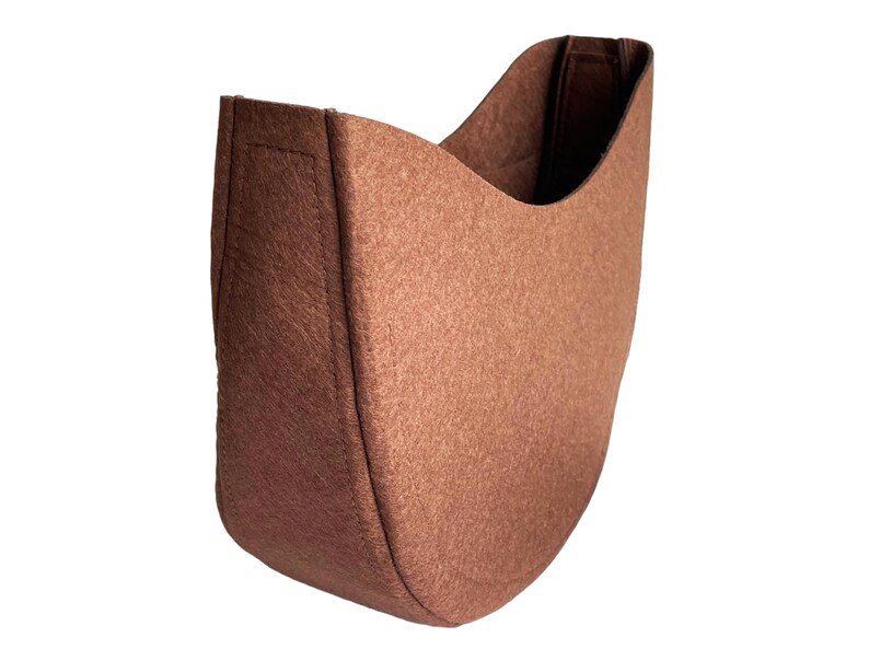 May include: A brown felt fabric planter with a curved shape. The planter is designed to be hung on a wall.