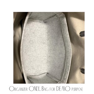 Pu&ograve; includere: Un organizer per borsa in feltro grigio chiaro con una forma rettangolare strutturata e angoli arrotondati, posizionato all'interno di una borsa tote in tela beige. Il testo "ORGANIZER ONLY, BAG FOR DEMO PURPOSE" &egrave; stampato in nero in basso.